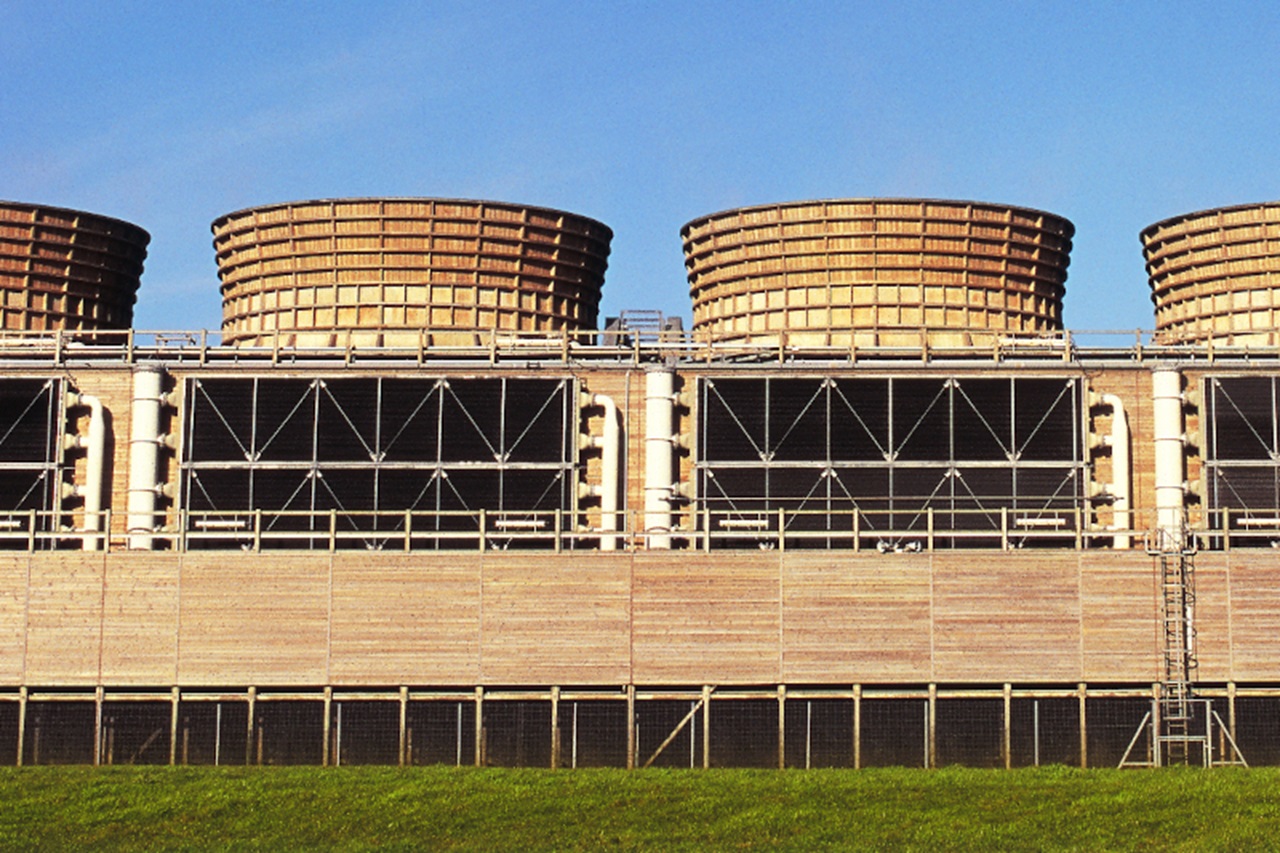 Cooling towers with a wooden structure and lattice framework against a clear blue sky.