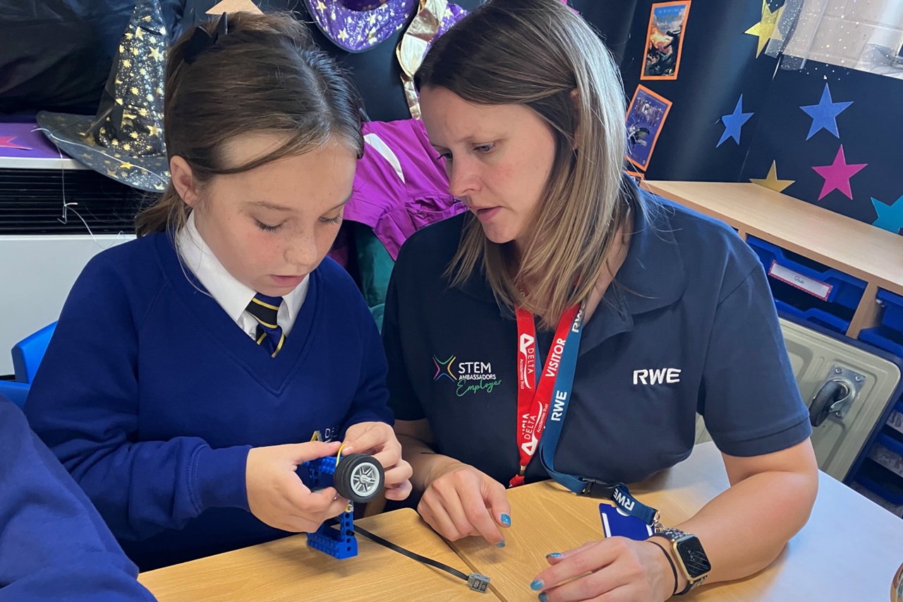A student and instructor assemble a model with wheels, focused on STEM activities in a colourful classroom.