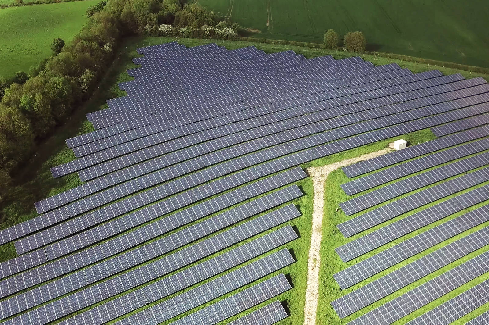 A large solar farm with numerous solar panels surrounded by green fields.