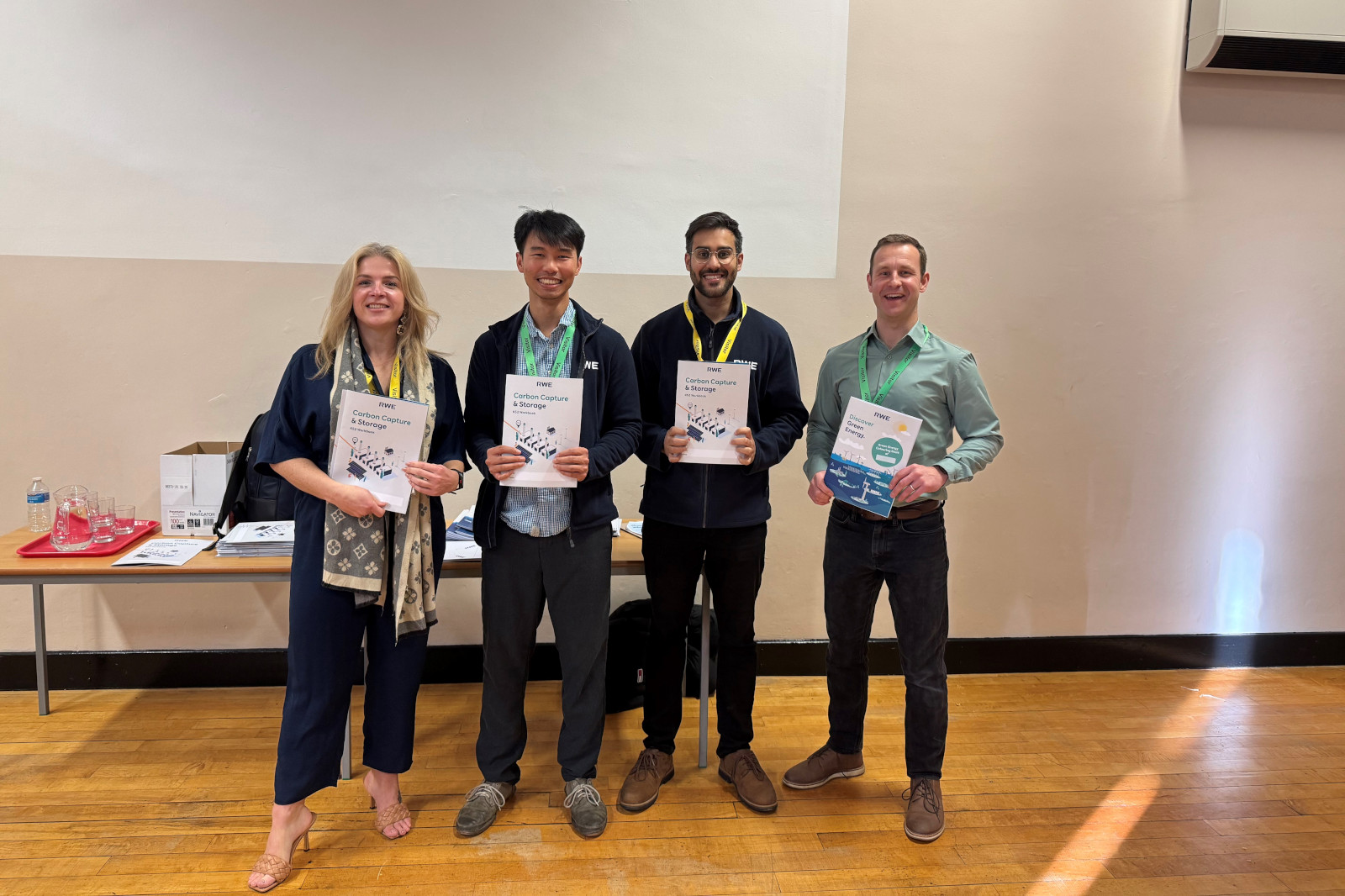 A group of people holding certificates, standing in front of a table with documents and glasses.