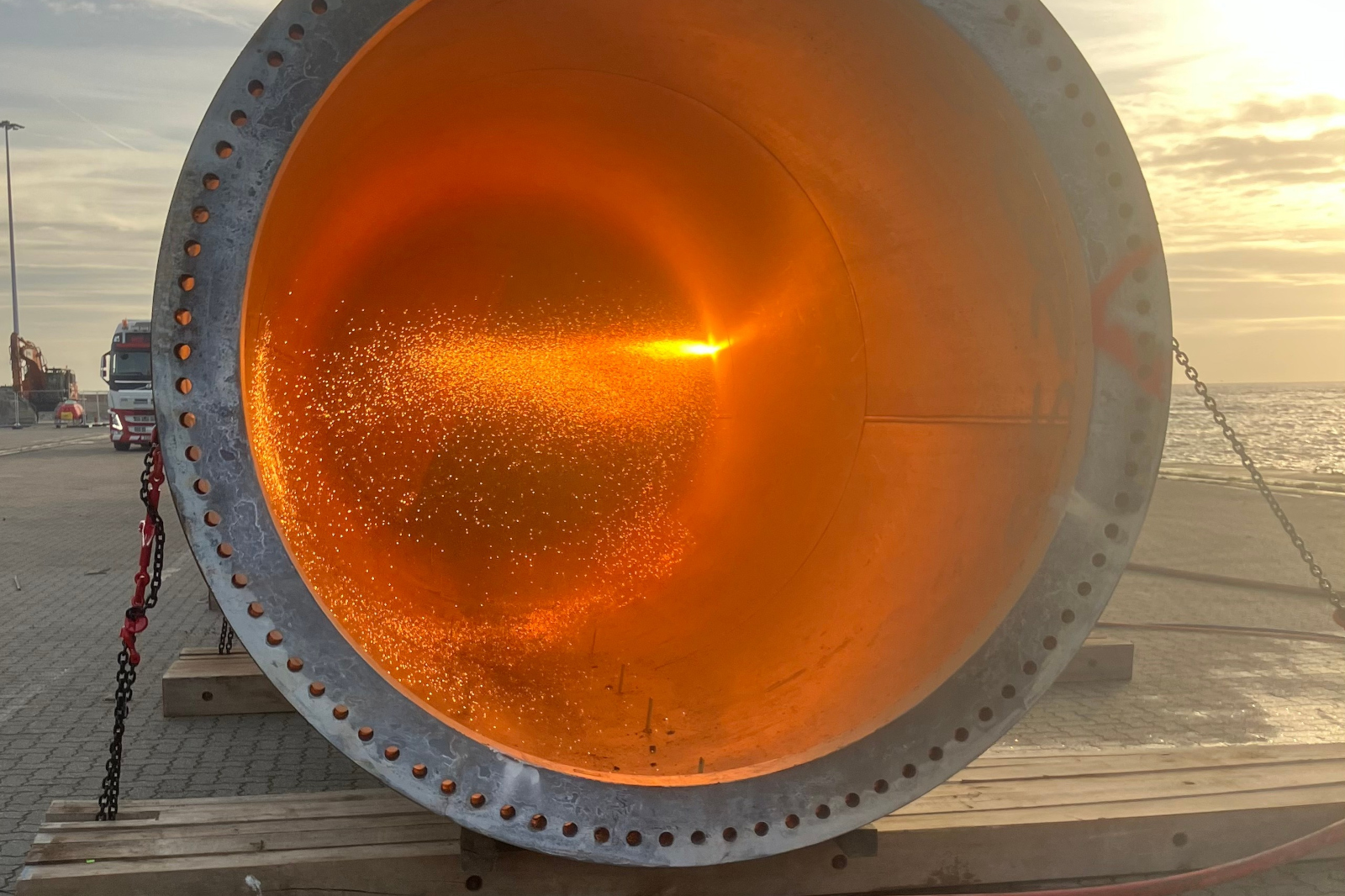 Large metal pipe with bright orange interior and sparks.