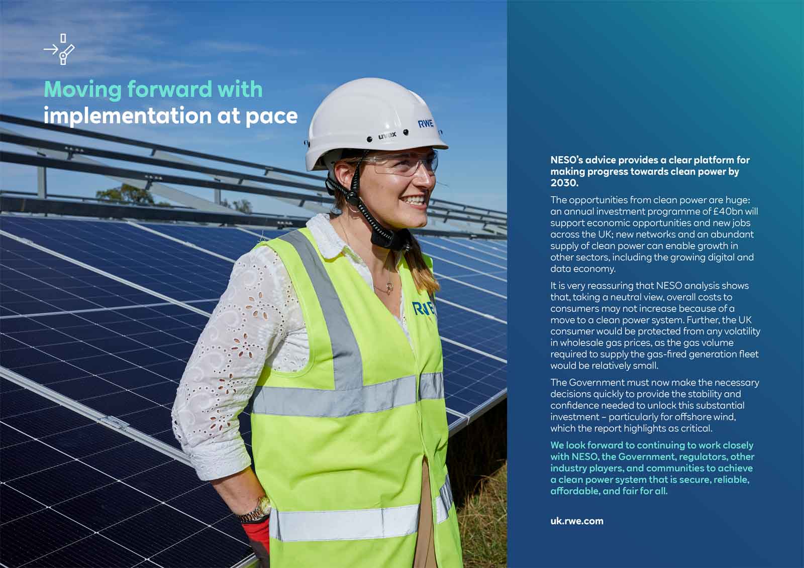 A woman in a hard hat and safety vest stands in front of solar panels, promoting clean energy advancements.