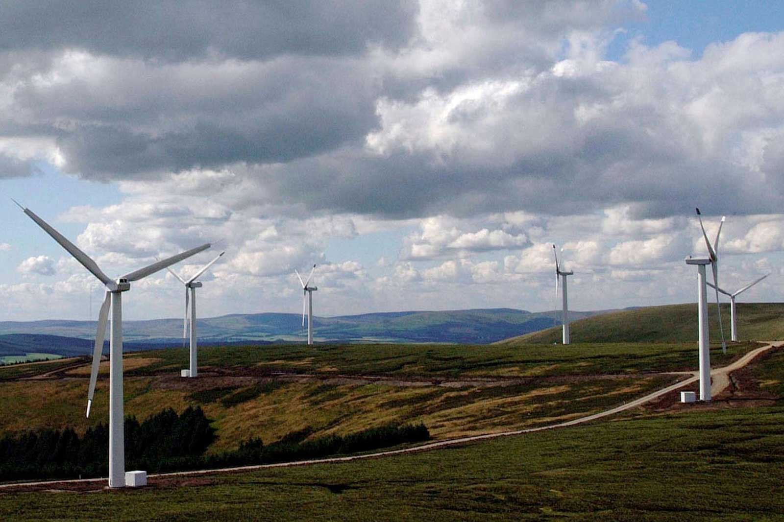 A landscape featuring several wind turbines on hills under a cloudy sky, showcasing renewable energy sources.