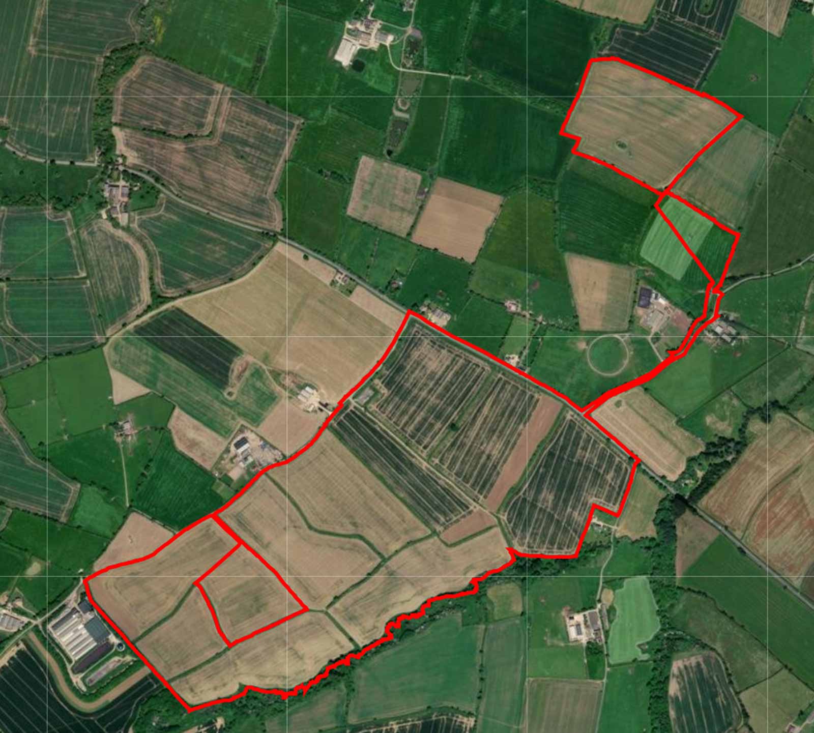 An aerial view of farmland with delineated boundaries marked in red, showcasing diverse crop sections and landscape features.