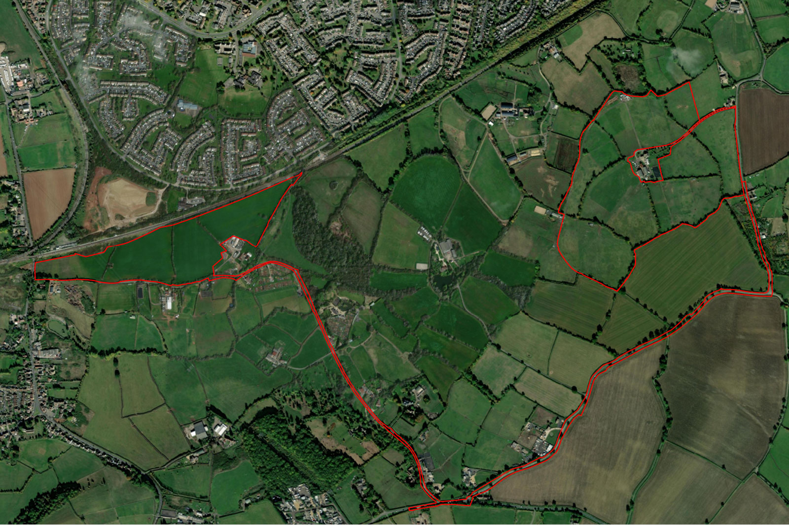 An aerial view of green fields and hedgerows, with red outlines marking walking paths and nearby residential areas.