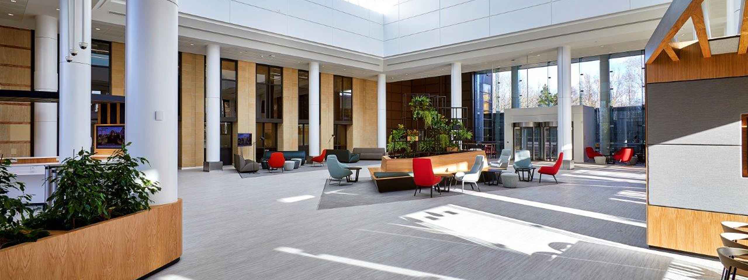 A spacious, modern lobby featuring tall pillars, comfortable seating areas, and abundant natural light from large windows.