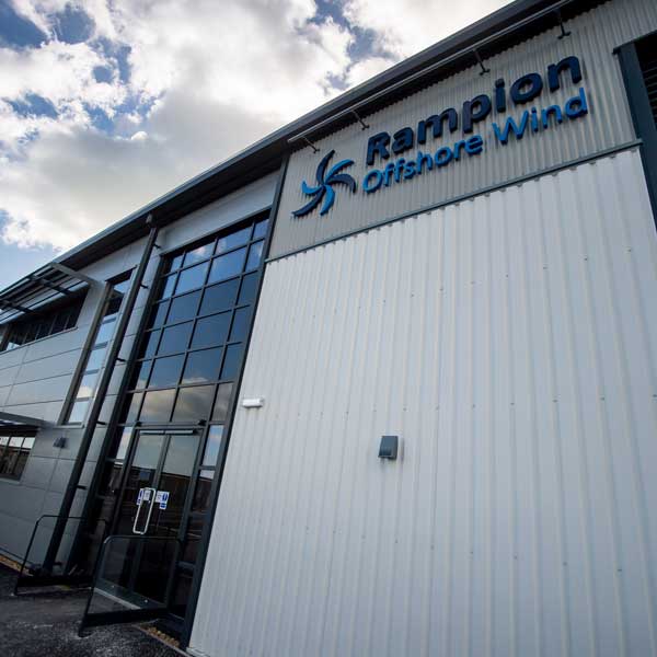 A modern building with large glass windows. The Rampion Offshore Wind logo is prominently displayed above the entrance.
